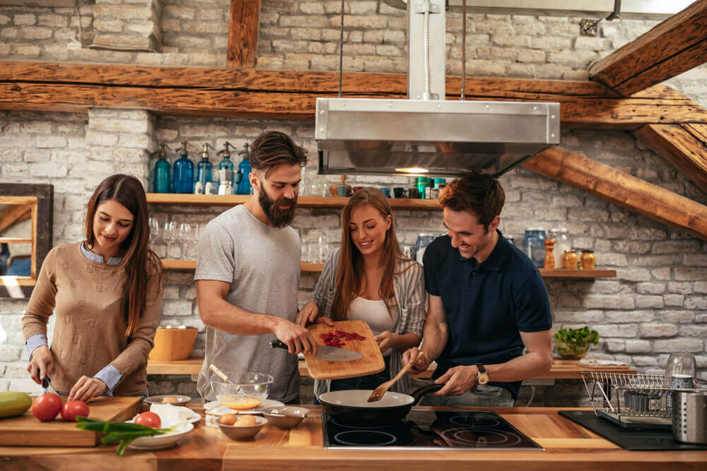Young adults making dinner together in rustic kitchen