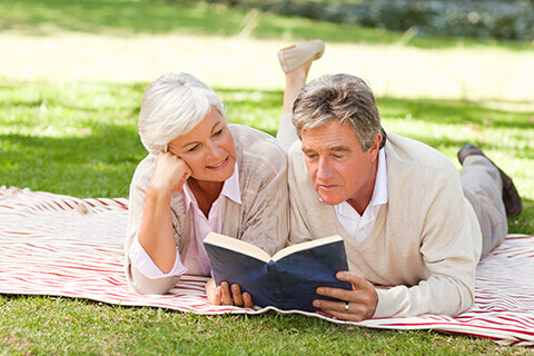 Mature couple reading on picnic blanket