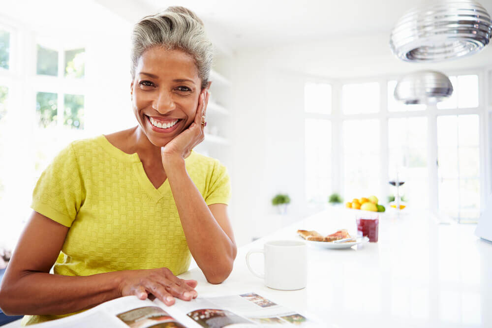 Woman reading a magazine while eating breakfast at home