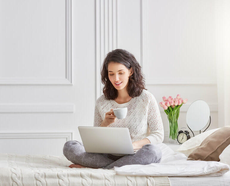 Young woman looking at her laptop drinking coffee