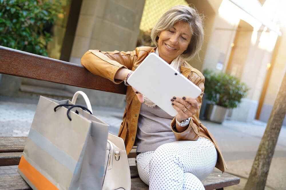 Mature woman on a bench looking at tablet
